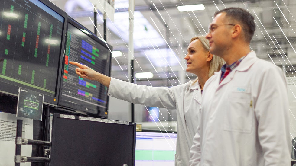 two manufacturing professionals analyzing data on a screen